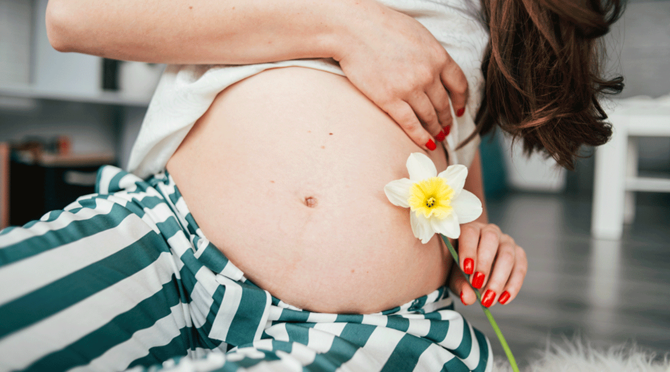 pregnant woman holding a daffodil flower