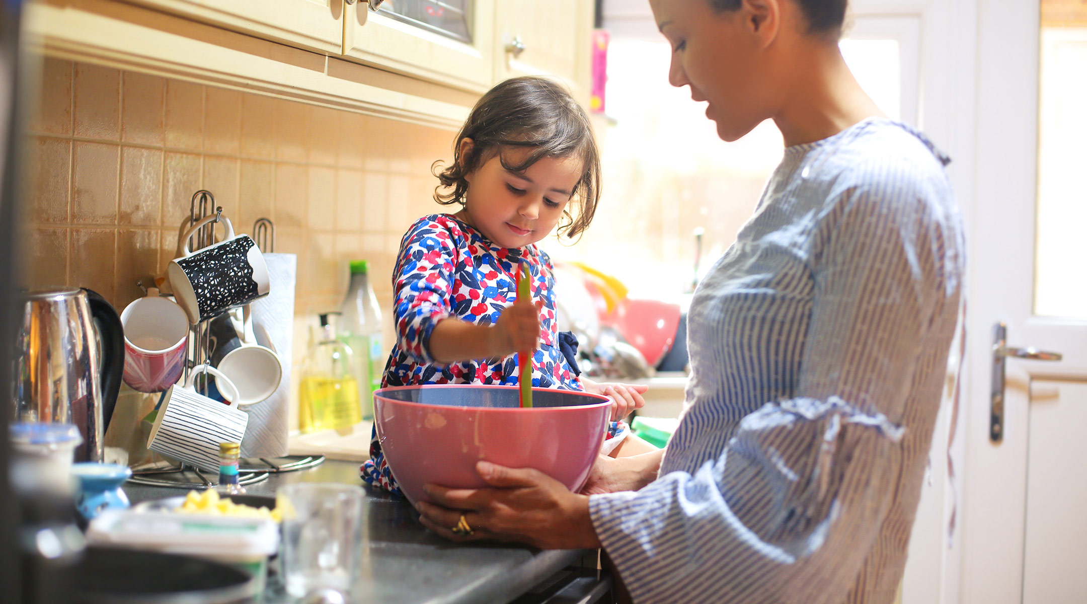 mom with toddler daughter cooking in kitchen
