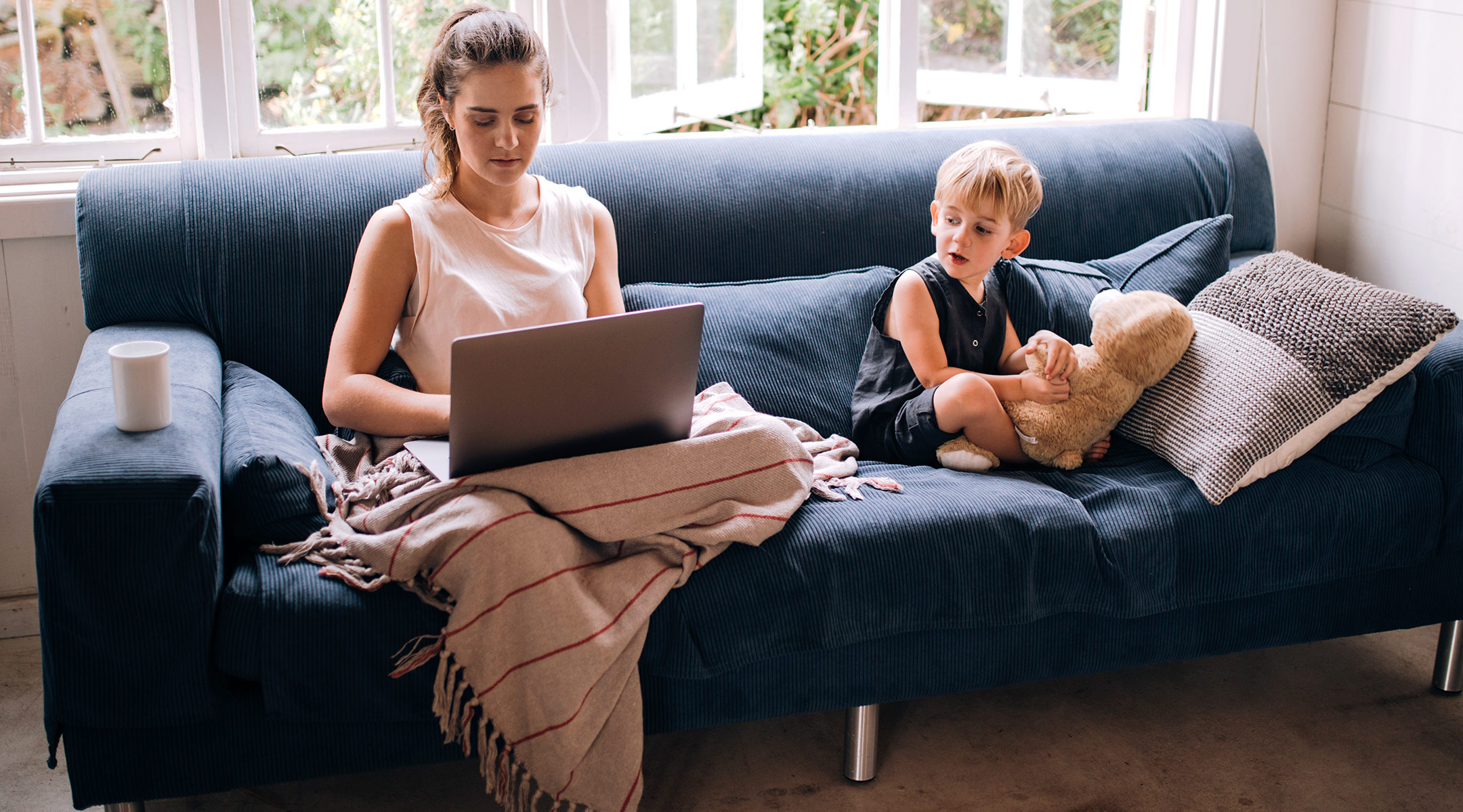 mom working on couch from home with her toddler next to her