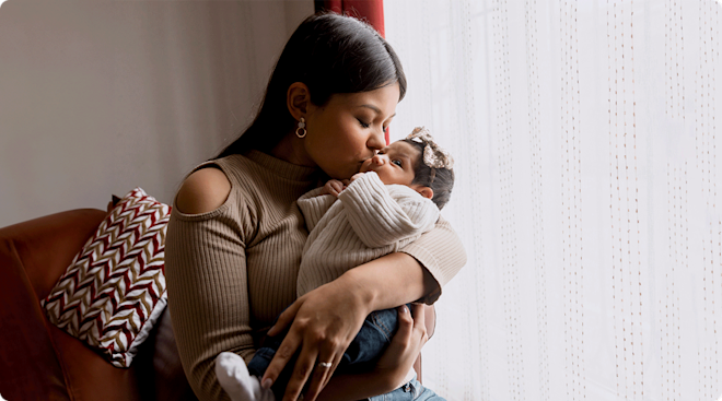 mom holding newborn baby at home postpartum
