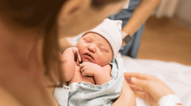 mom holding newborn baby in delivery room