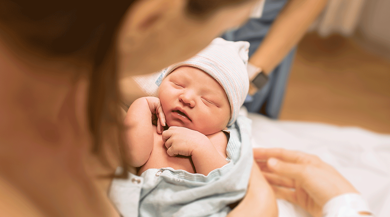 mom holding newborn baby in delivery room