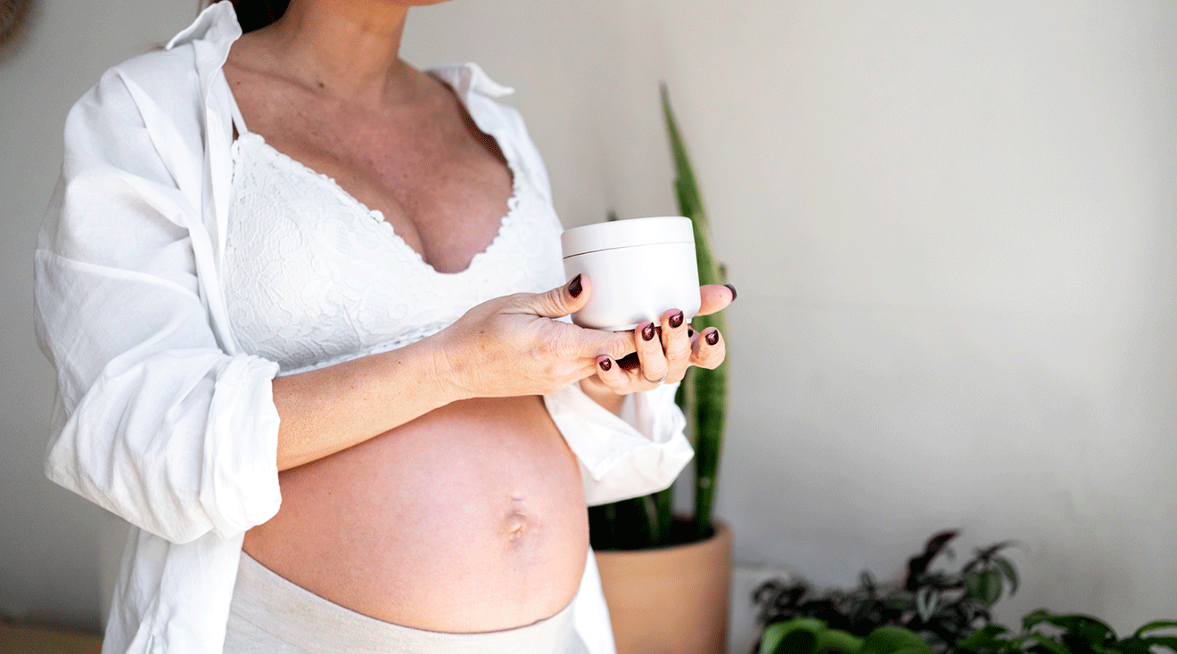 pregnant woman holding a tub of lotion