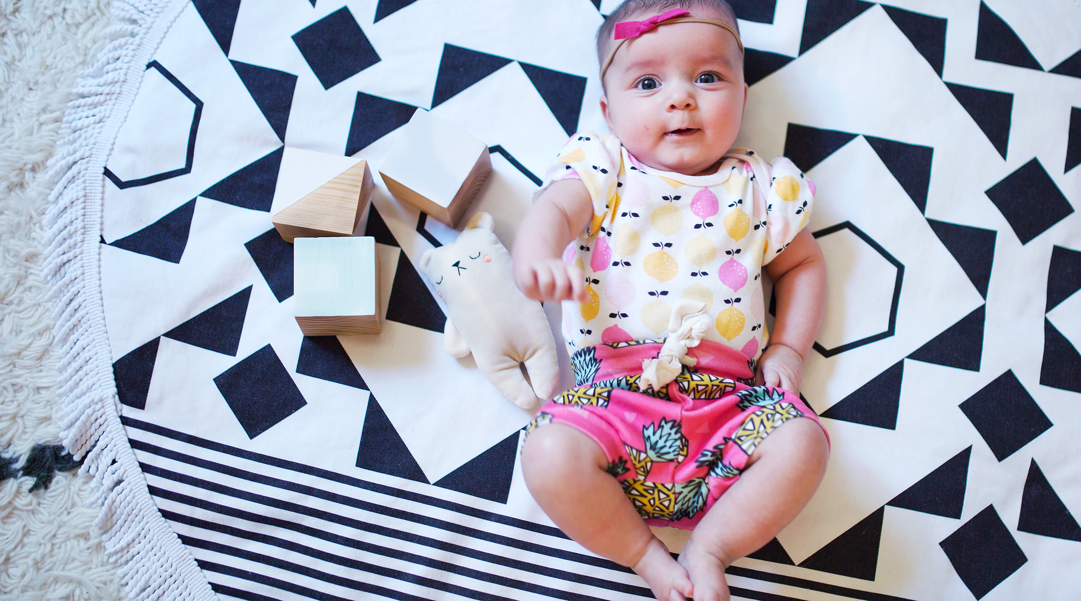 baby on rug surrounded by learning blocks