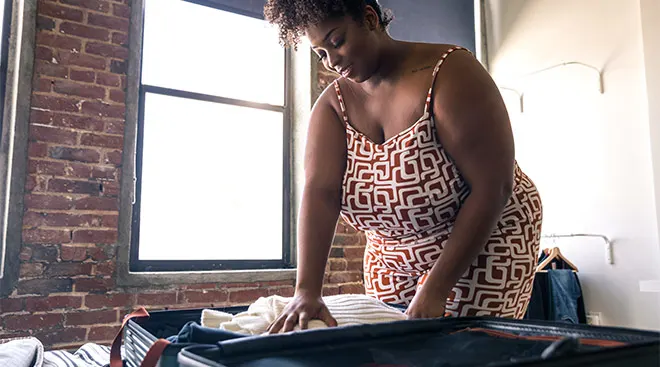 Mom packing a suitcase for a trip on her bed.