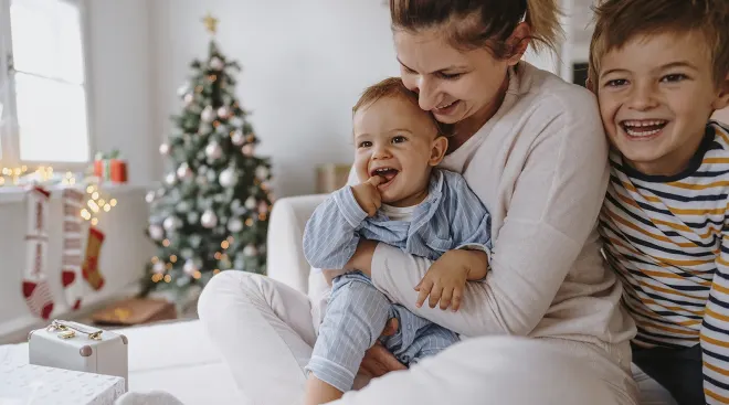 mother with baby and child laughing on christmas morning