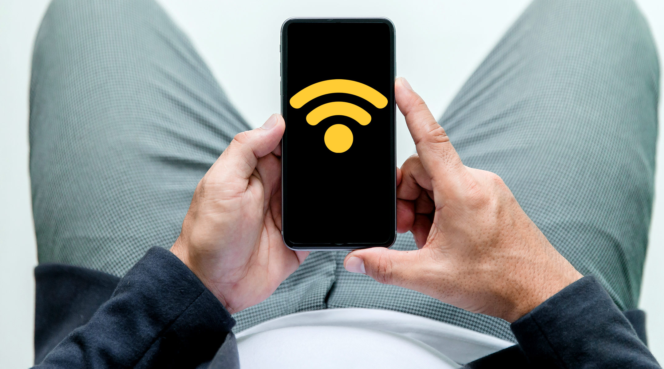 man sits down while looking at wifi signal on phone