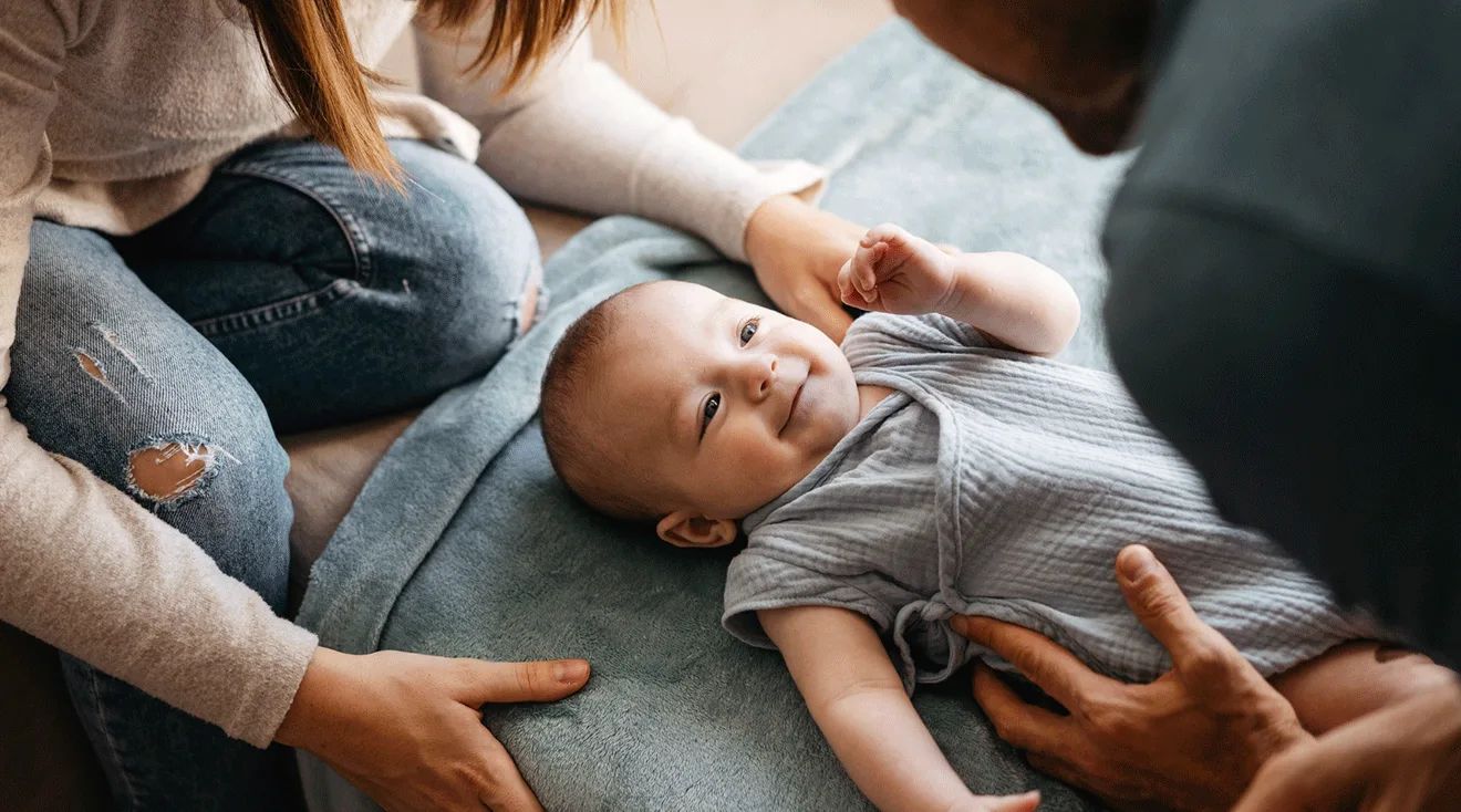 mom and dad with smiling infant at home