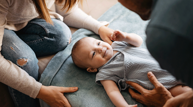 mom and dad with smiling infant at home