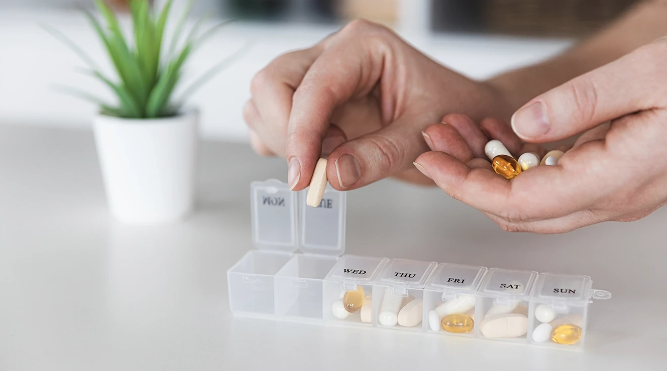 hands placing vitamins into pill organizer