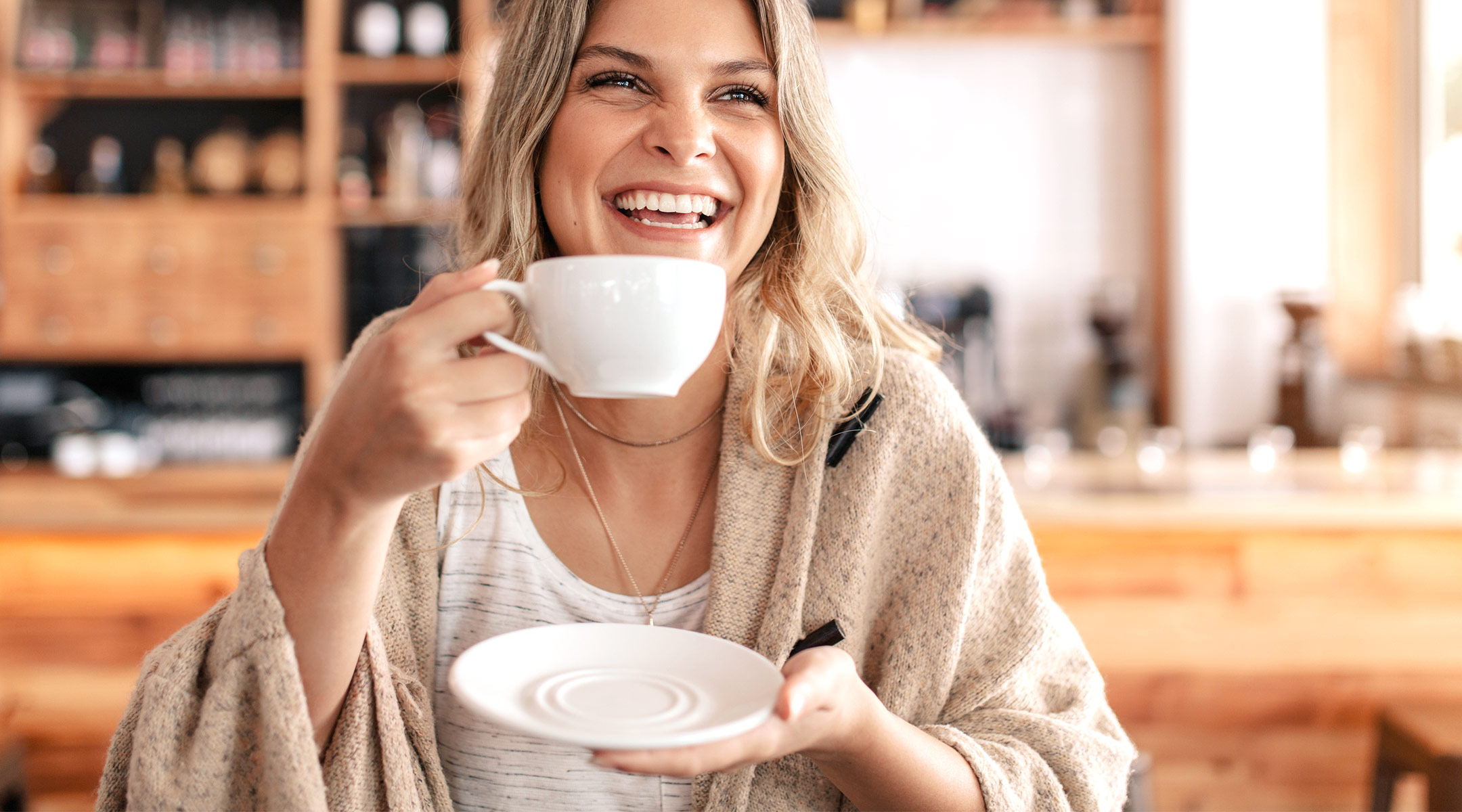 woman laughing and drinking coffee in cafe