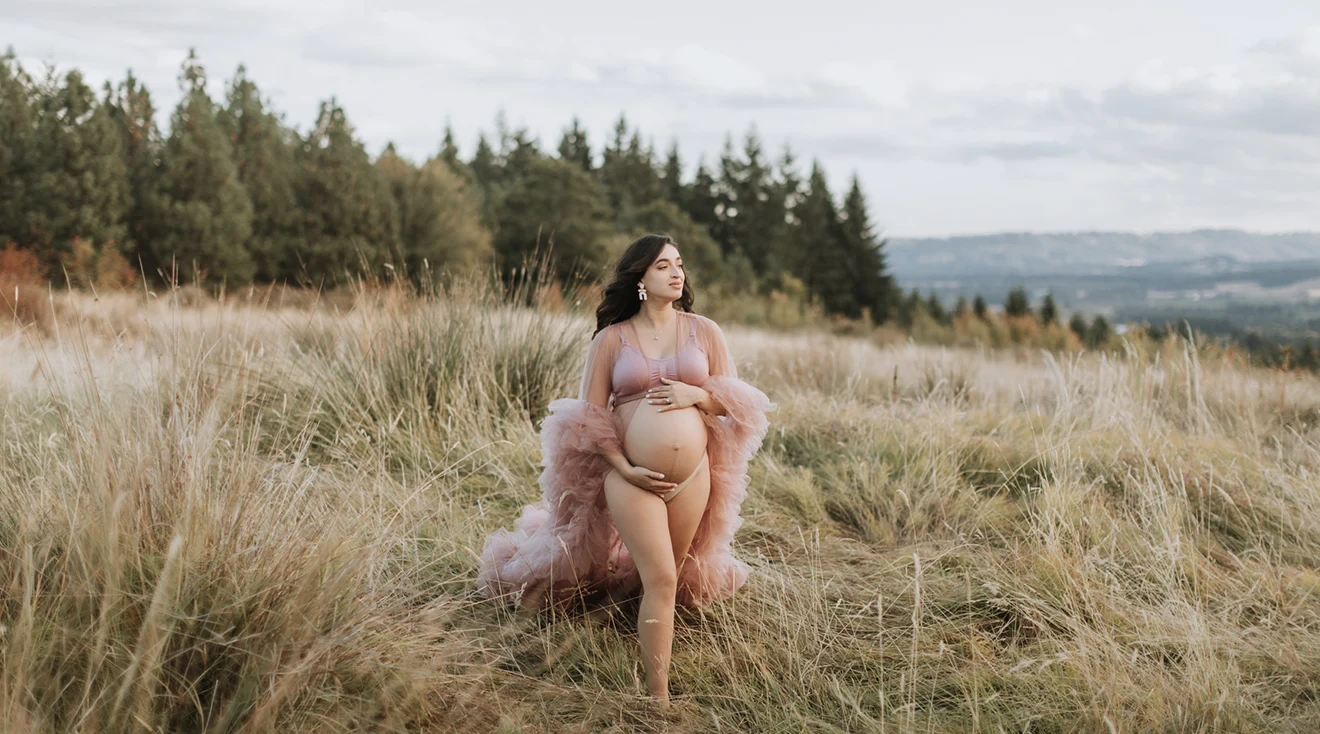 pregnant woman in a field wearing a pink robe