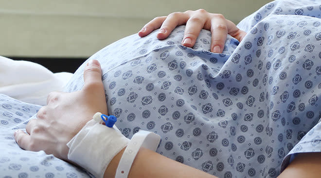 close up of pregnant woman's belly in hospital bed before labor 