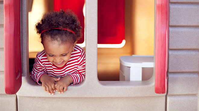 toddler inside playhouse and laughing by window