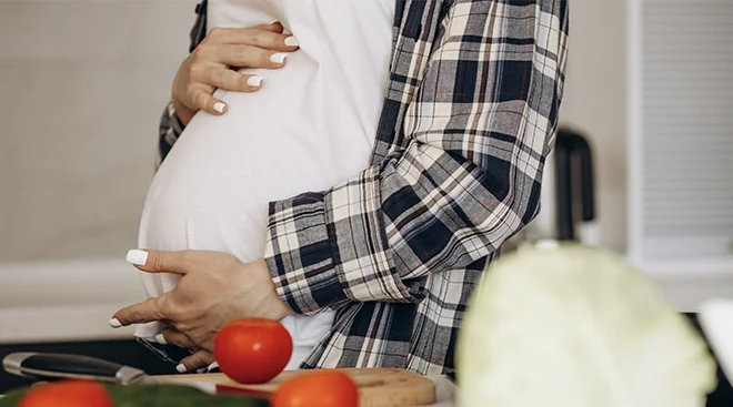 pregnant woman preparing food in kitchen