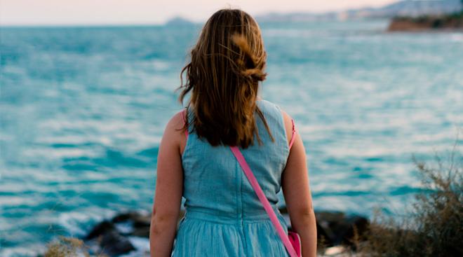 sad woman standing alone by body of water