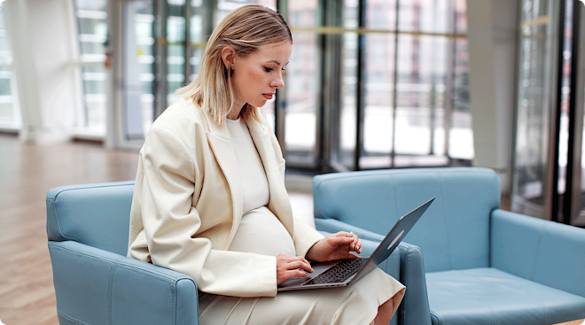 corporate pregnant woman working on laptop at work