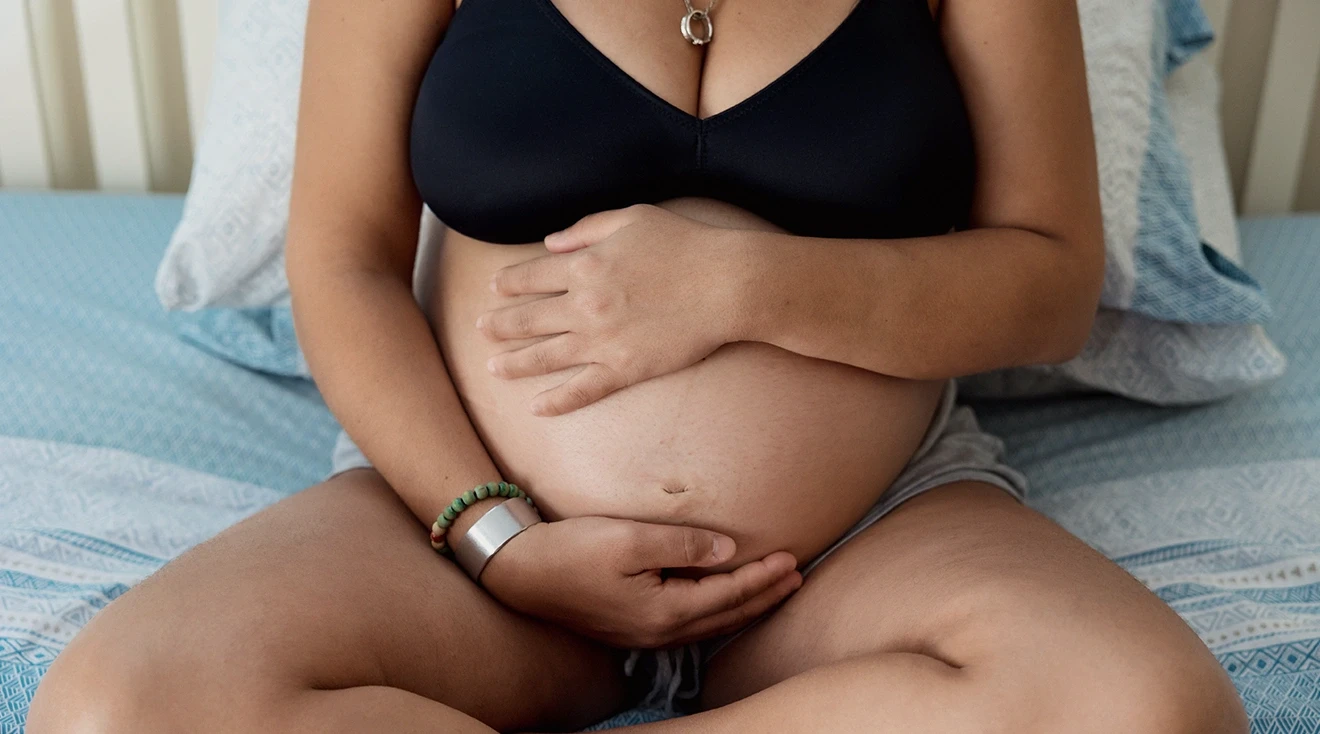 close up of pregnancy woman sitting on bed at home