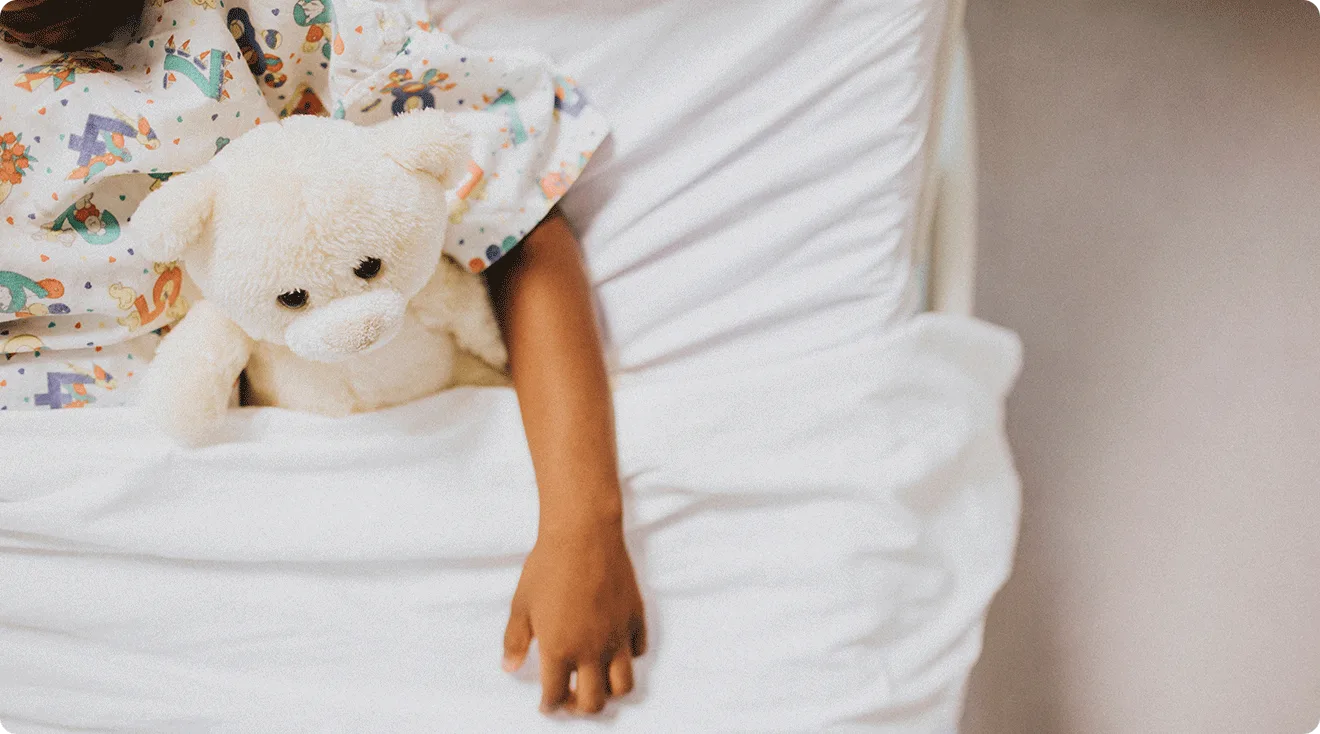 child in hospital bed with stuffed animal