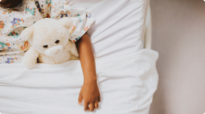 child in hospital bed with stuffed animal