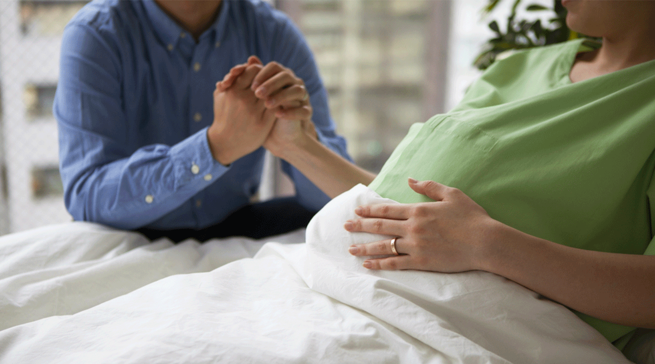 pregnant woman holding husband's hand during childbirth in hospital bed