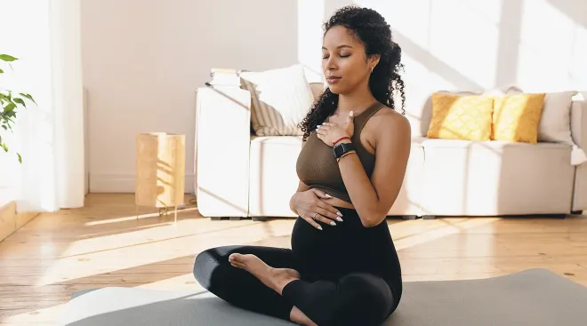 pregnant woman practicing meditation at home on yoga mat