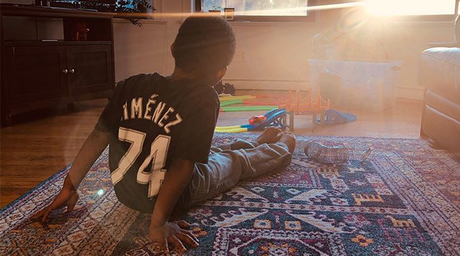 little boy wearing sports t-shirt sits in living room