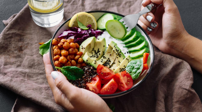woman's hands eating healthy quinoa bowl