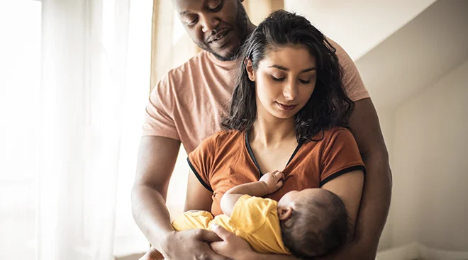 mother and father holding their baby at home