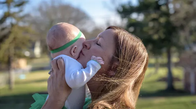 mother kissing baby dressed in st. patrick's day outfit