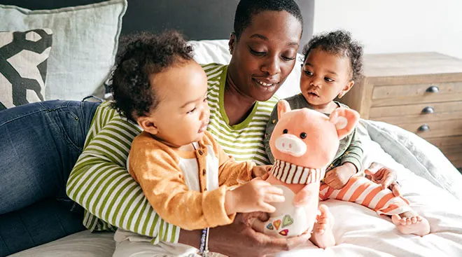 Busy mom entertains her young children at home with a stuffed animal pig.