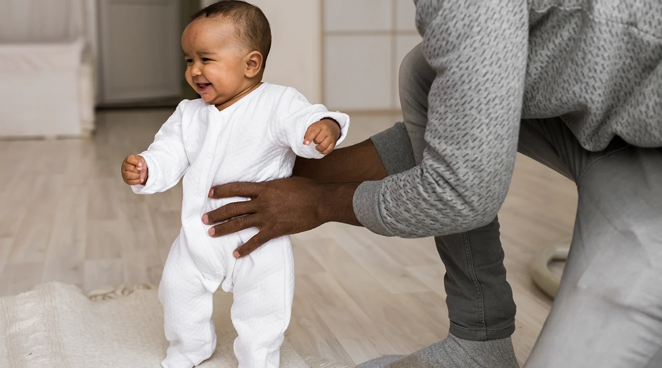 Parent holding baby while baby tries to stand 