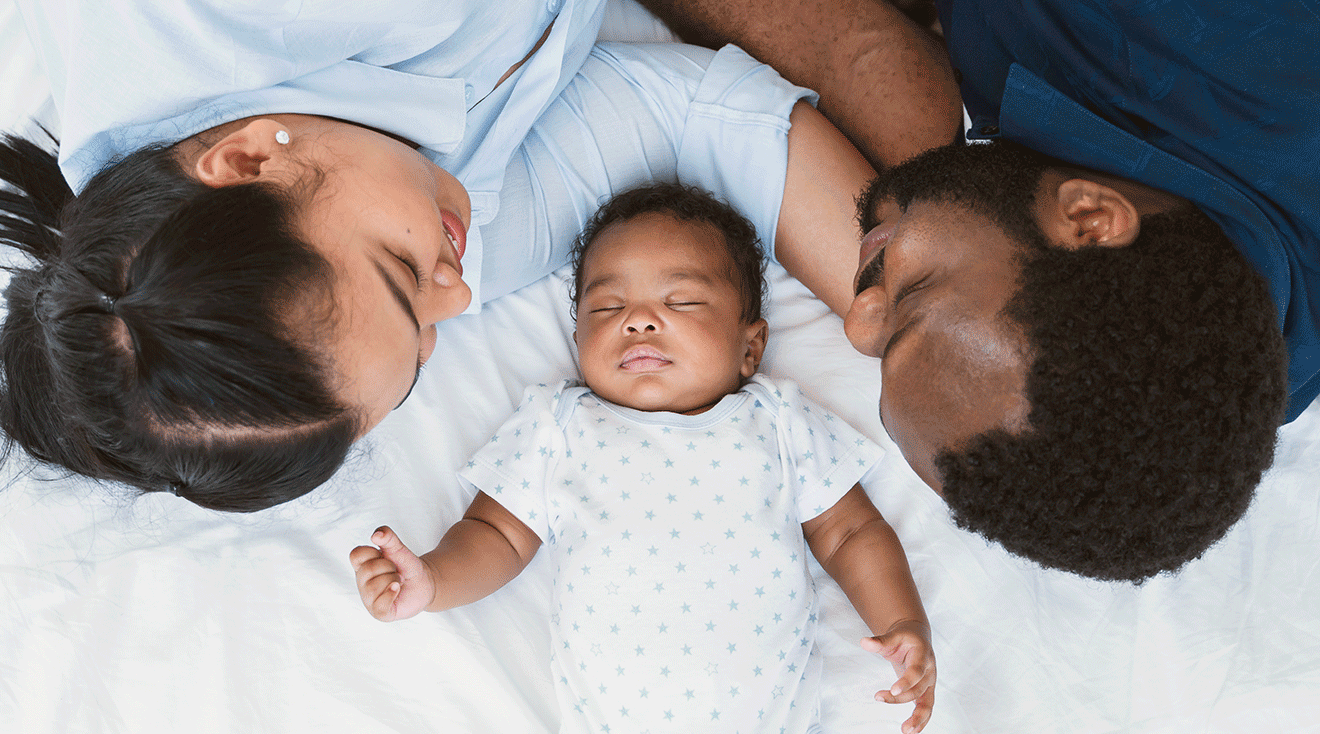 mom and dad laying with sleeping newborn baby