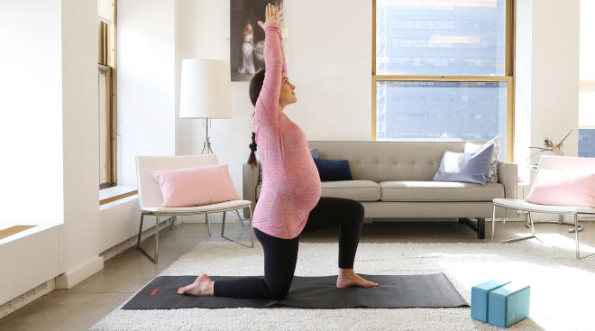 pregnant woman doing yoga in living room