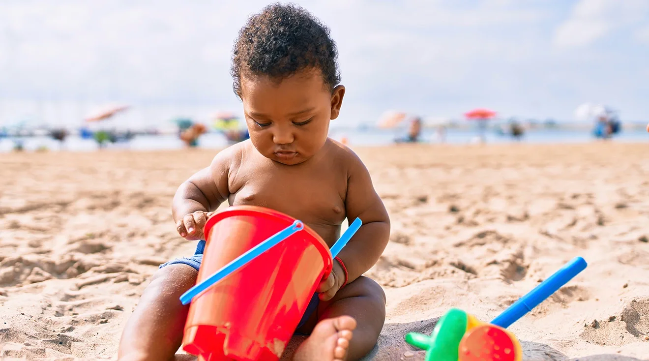 baby playing with toys on the beach