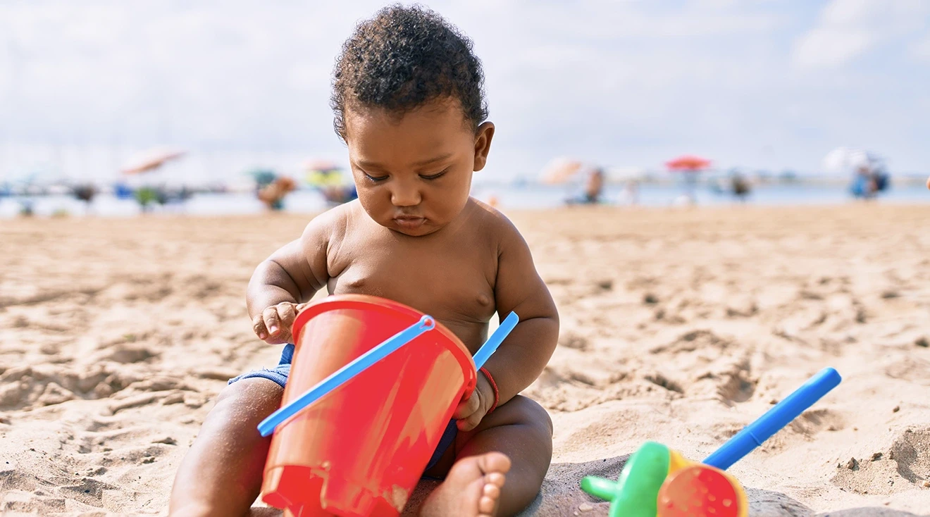 baby playing with toys on the beach