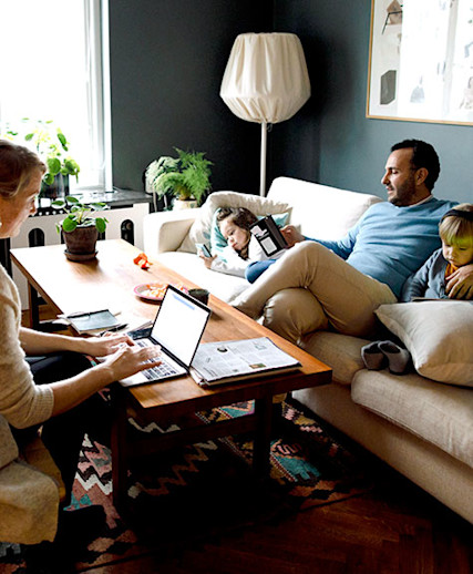 family with young children looking at their digital devices at home on the couch