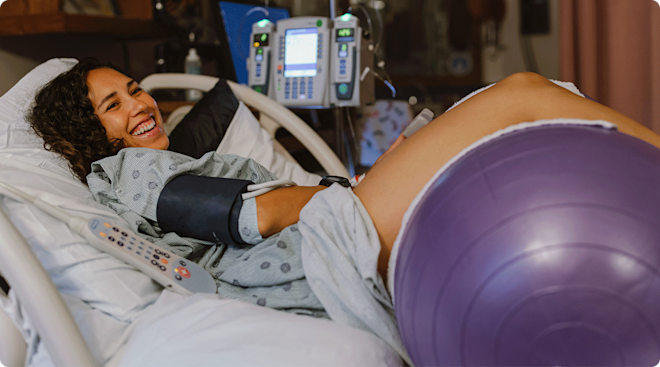 pregnant woman using labor ball in hospital bed during labor