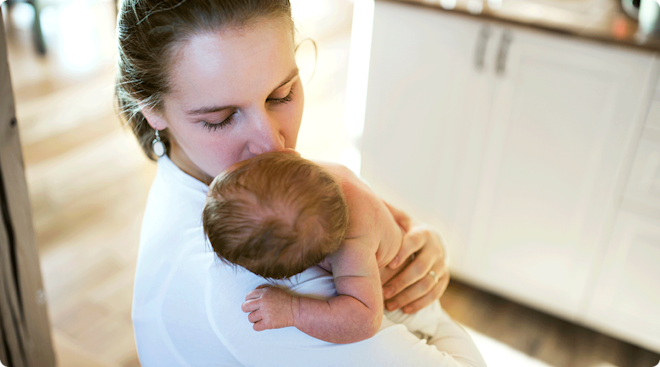 postpartum mom holding newborn baby at home