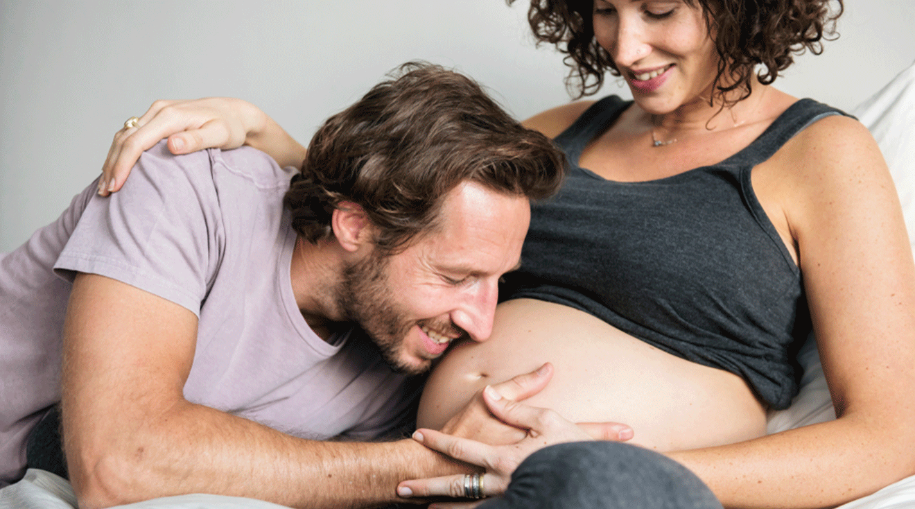 father smiling with pregnant belly