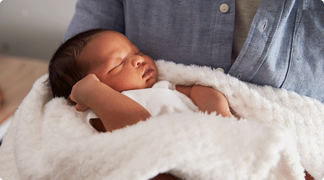 newborn baby sleeping in fathers arms