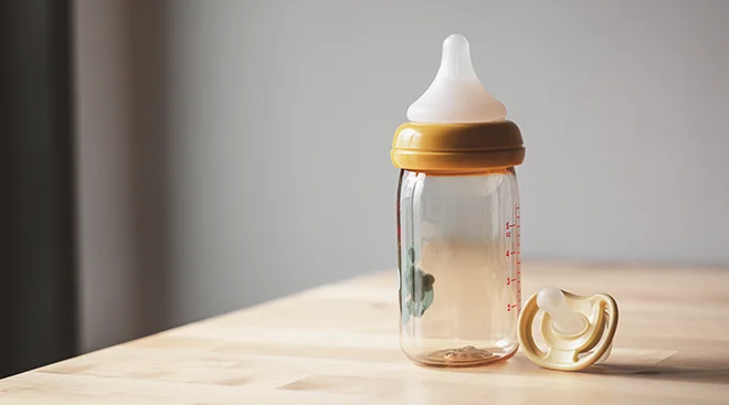 empty baby bottle and pacifier on counter in home