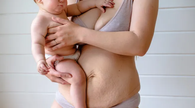 mother holding baby showing post-baby body