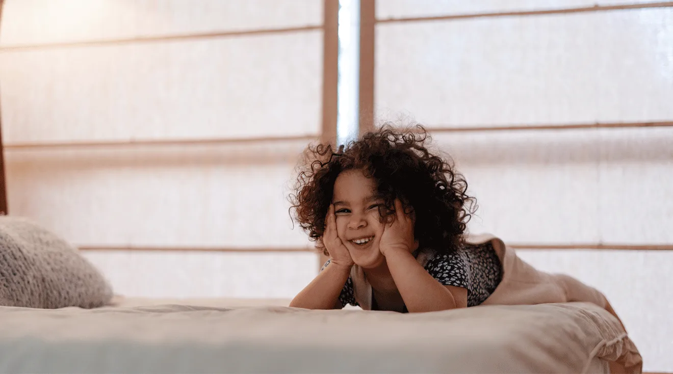 toddler girl laughing in bed at home