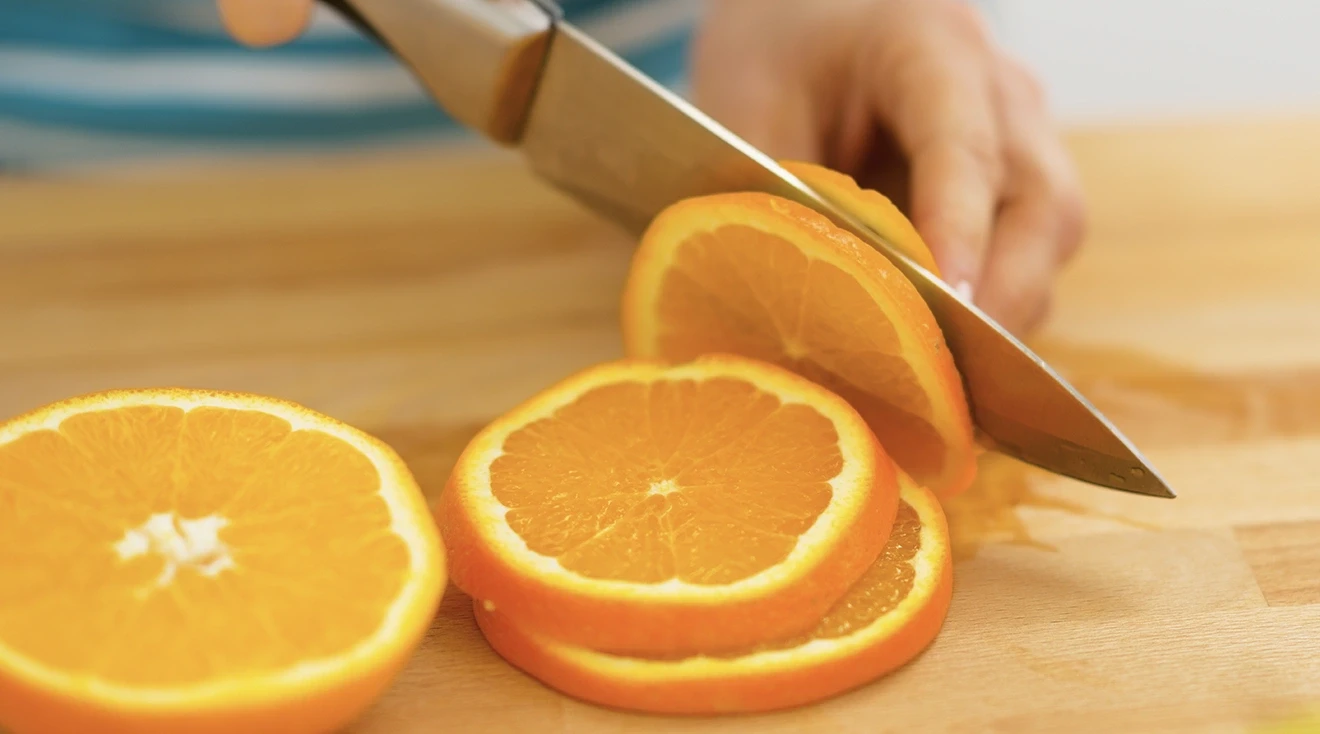 close up of woman cutting an orange