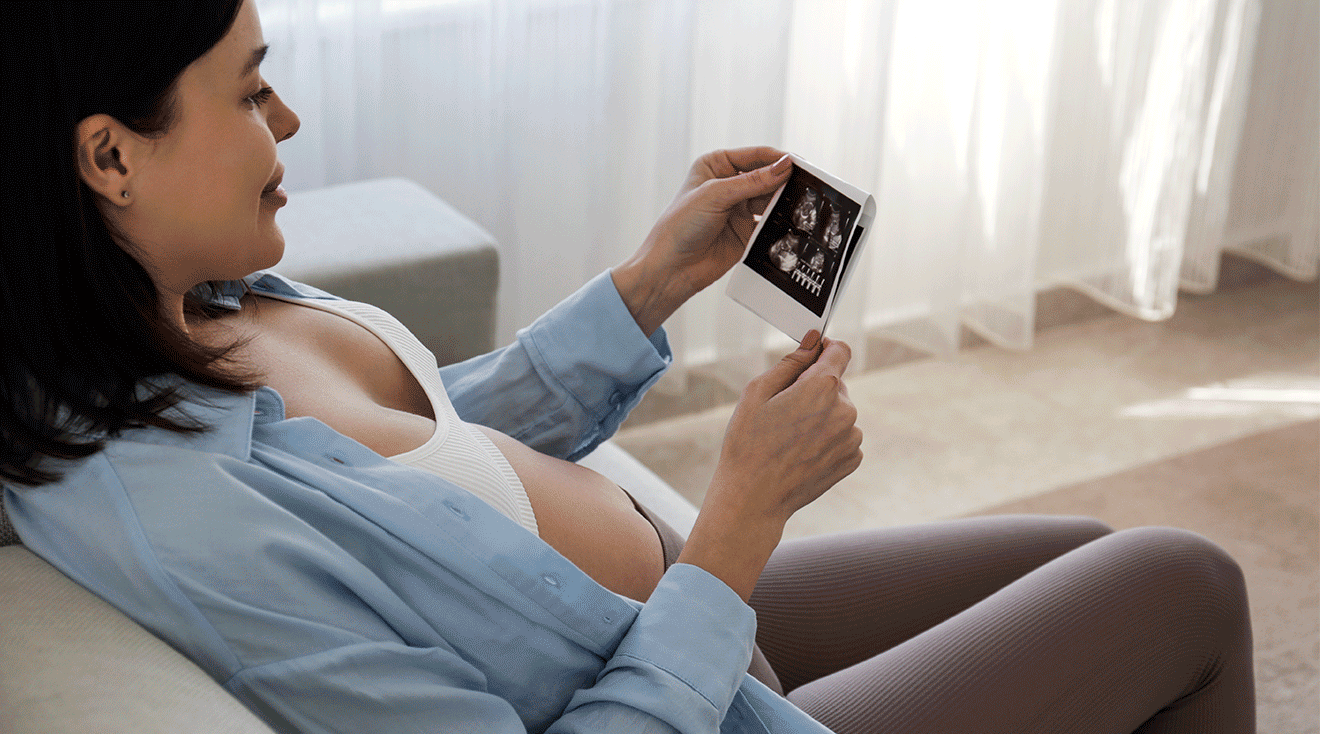 pregnant woman looking at first trimester ultrasound photo