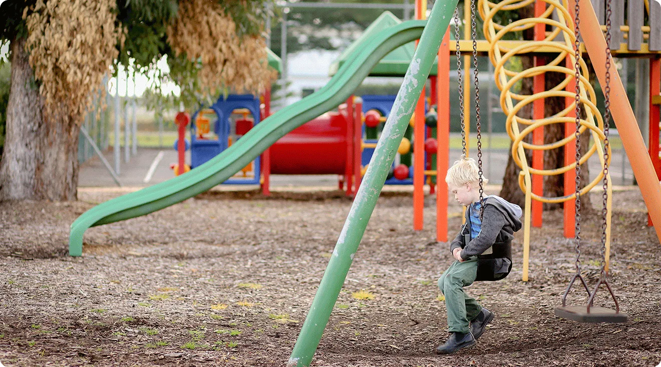 lonely child sitting on swing on the empty playground