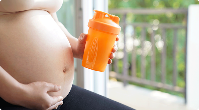 pregnant woman holding workout drink shake bottle