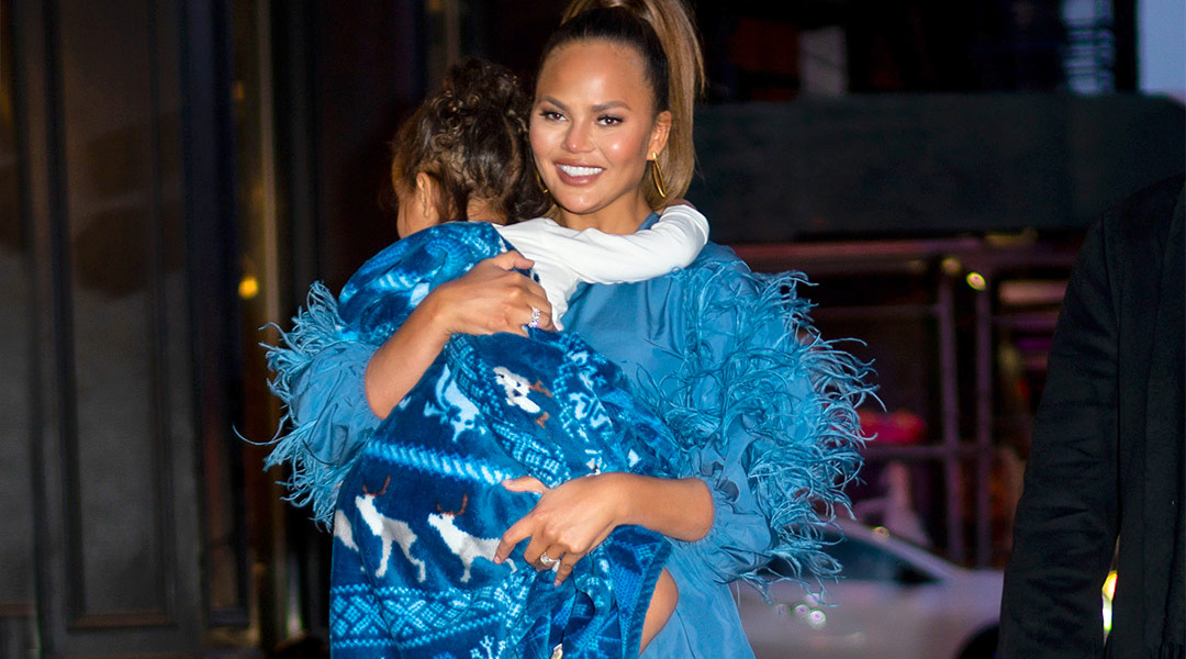 chrissy teigen walking and holding her daughter