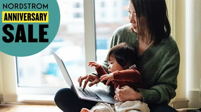mother with baby in lap shopping on laptop at home